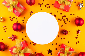 Christmas and New Year compositions with gifts boxes wrapped in red paper with golden ribbon bow on yellow background with empty circle for your greetings,
