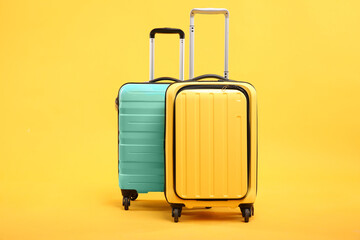 Two different bright suitcases on yellow background