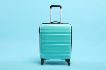One new turquoise suitcase on light blue background