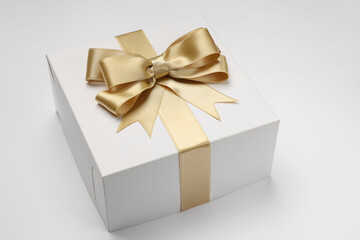 Gift box with golden bow on light grey background