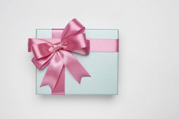 Gift box with pink bow on light grey background, top view