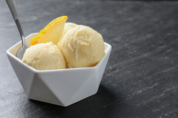 Scoops of tasty melon sorbet with fresh fruit and spoon in bowl on grey textured table, closeup. Space for text