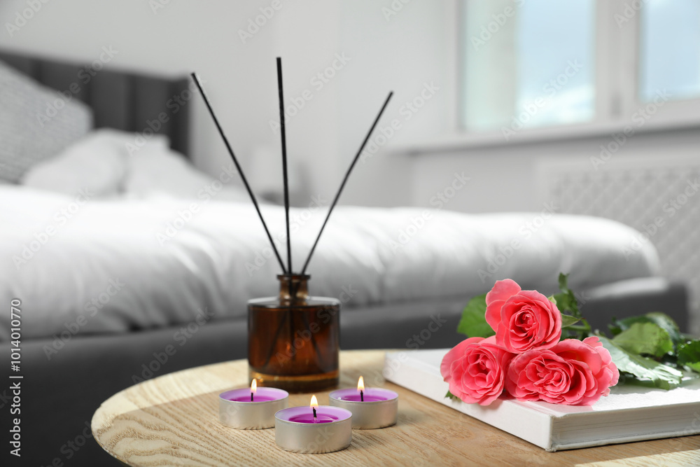 Poster Burning candles, rose flowers, book and reed diffuser on wooden table indoors