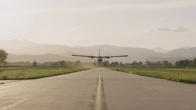 Evening aircraft takeoff on a quiet runway with mountains in the background
