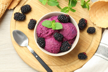 Delicious blackberry sorbet with fresh berries in bowl, waffle cones and spoon on wooden table, top view