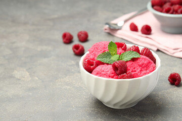 Delicious raspberry sorbet, fresh berries and mint in bowl on gray textured table, space for text
