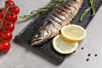 Delicious grilled mackerel, rosemary, lemon, tomatoes and peppercorns on grey table, closeup