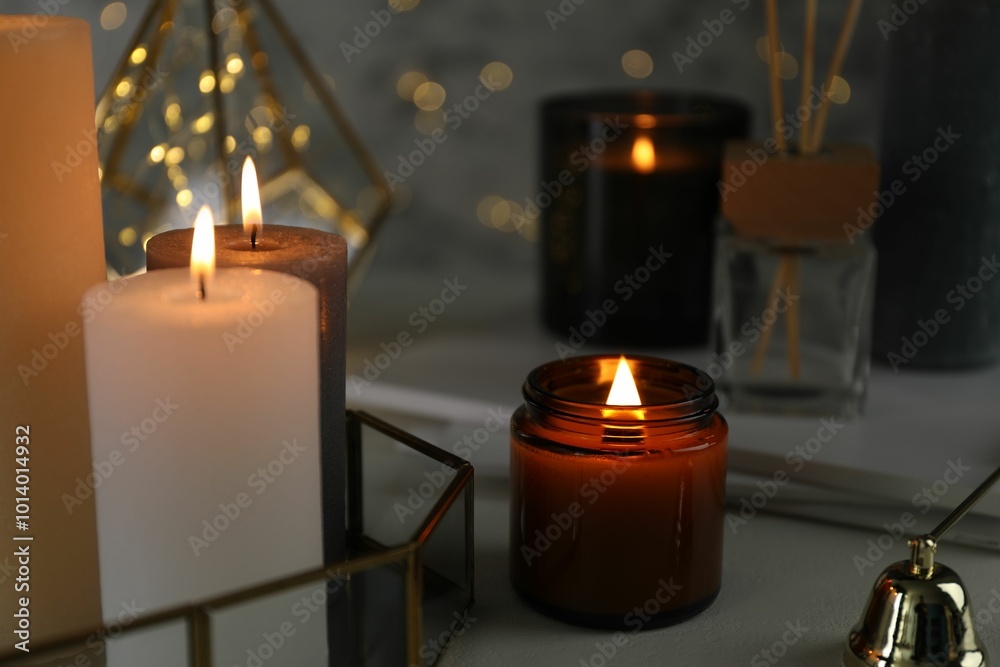 Sticker Beautiful burning candles on table against blurred lights, closeup