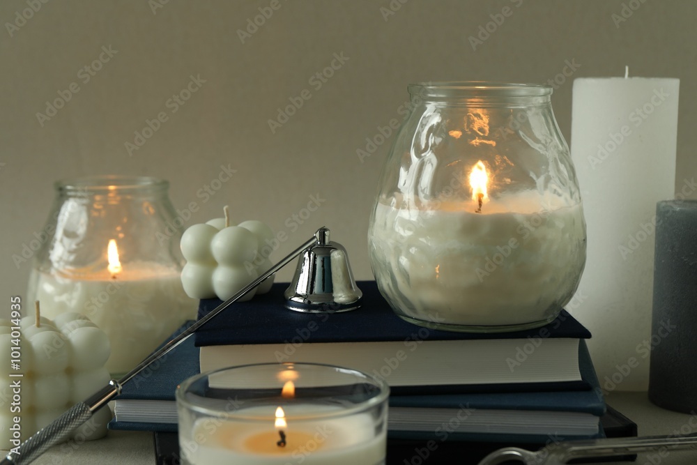 Wall mural Beautiful burning candles, books, candle snuffer and wick trimmer on gray table, closeup