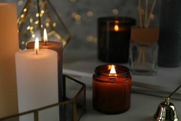 Beautiful burning candles on table against blurred lights, closeup