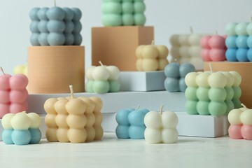 Many beautiful bubble candles and podiums on white table
