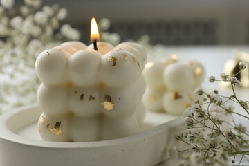Stylish bubble candles and gypsophila flowers on table, closeup