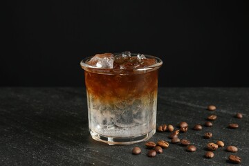 Refreshing espresso tonic drink and coffee beans on dark table
