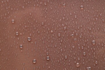 Water drops on brown background, top view