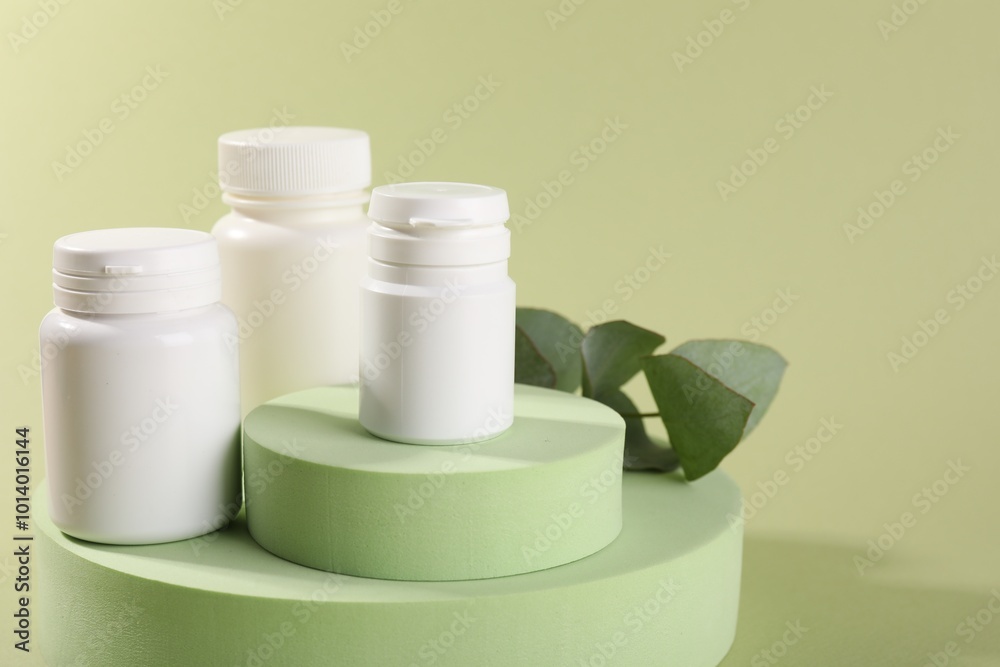 Poster Plastic medical bottles, leaves and podiums on green background, closeup