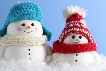 Cute decorative snowmen against light blue background, closeup