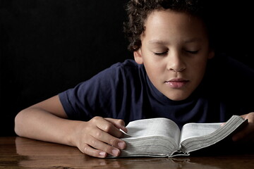 little boy praying to God with hands together on black background with people stock photo stock image