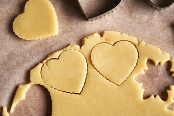 Cutting out heart shapes from rolled out dough to prepare traditional Linzer Christmas cookies