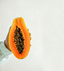 fresh, ripe papaya sliced ​​open on orange background, harsh sunlight