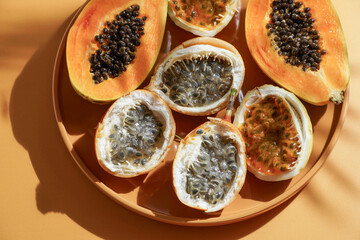 exotic tropical fruits,  passion fruits and dragon fruit, ripe papayas. on a bamboo tray with green leaves, stone background