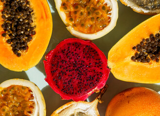exotic tropical fruits,  passion fruits and dragon fruit, ripe papayas. on a bamboo tray with green leaves, stone background