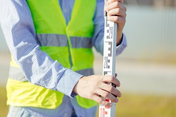 Worker is unfolding leveling rod on construction site.