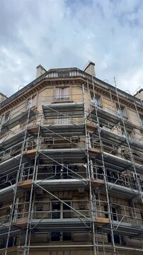 Un immeuble de pierre en r&eacute;novation, prot&eacute;g&eacute; par un &eacute;chafaudage au format vertical.