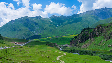Panoramic view from the grassy hill on the Kazbek mountains and the green valley crossed