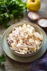 Salad with squid, vegetables and mayonnaise for lunch on a gray background. vertical photo. Close-up.