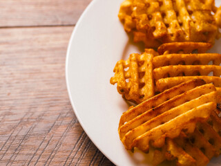 Cooked potato chips fries in a lattice shape on a white plate. Selective focus. Marketing move to...