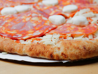 Uncooked pizza with meat products and buffalo cheese. Close up. Italian style dish with high quality ingredients. Fast food with premium products.