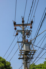 electric poles with complicated cables and transformers in the background of the blue sky