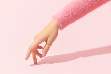 Beautiful groomed womans hand with pink matte nail design on a pink background. Manicure, pedicure beauty salon.