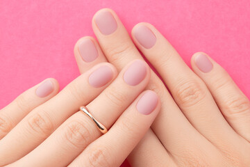 Womans hands with trendy pink matte manicure close-up. Beauty salon.