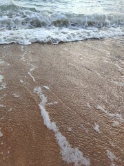 Ocean waves gently washing over wet sandy beach on a calm, peaceful day