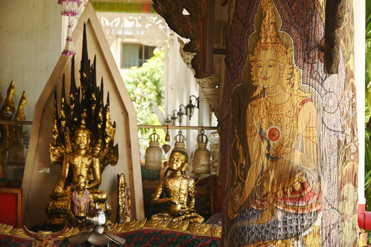 Golden Sitting Buddha statue and there is a serpent covering the back and Upagupta buddha decorated front of Buddhist Thai Church at Wat Naga Prok temple.