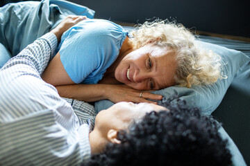 Middle aged lesbian couple cuddling in bed