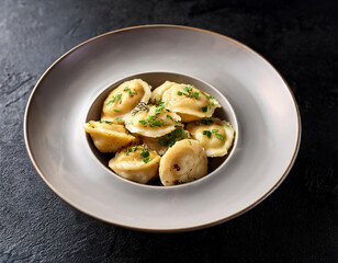Boiled dumplings with  green dill in a white plate over dark stone background