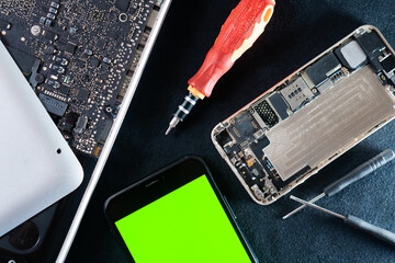 Disassembled Electronics with Tools and Green Screen Smart phone