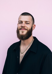 Obraz premium portrait of a handsome male model with a medium length beard, short hairstyle, black shirt unbottoned with gold chain, light pink background