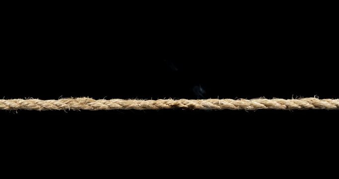 Rope stretched tight and slowly burning apart, finally snapping and breaking in two. Concept showing stress or stressful situations like divorce separation, deadlines, failure, or nervous tension.