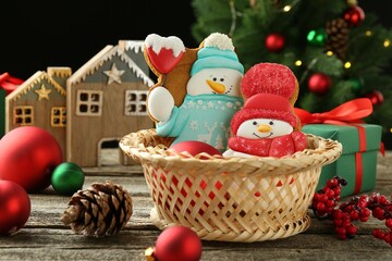 Delicious cookies in shape of snowmen and Christmas decor on wooden table