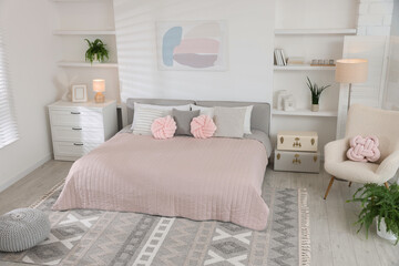 Large bed, houseplants and decorative elements in room. Stylish bedroom interior