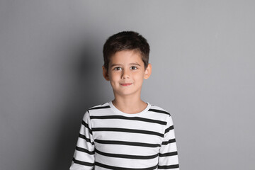 Portrait of cute little boy on grey background