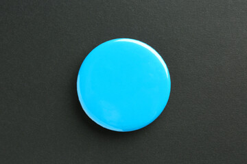Blue button badge on black background, top view. Mockup for design