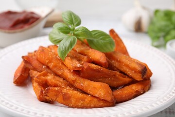 Sweet potato fries and basil on table, closeup