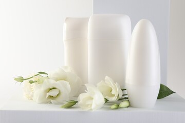 Different deodorants and beautiful eustoma flowers on white background