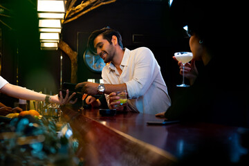 Caucasian man using mobile banking application on smartphone scan QR code making online payment while hangout party at restaurant bar. Electronic banking and Contactless payment technology concept.