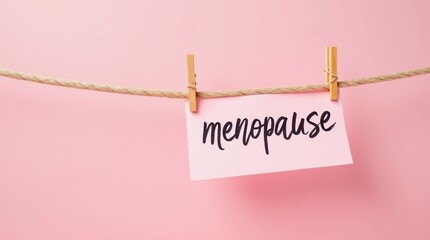 Pink paper with menopause text on clothesline against pink background