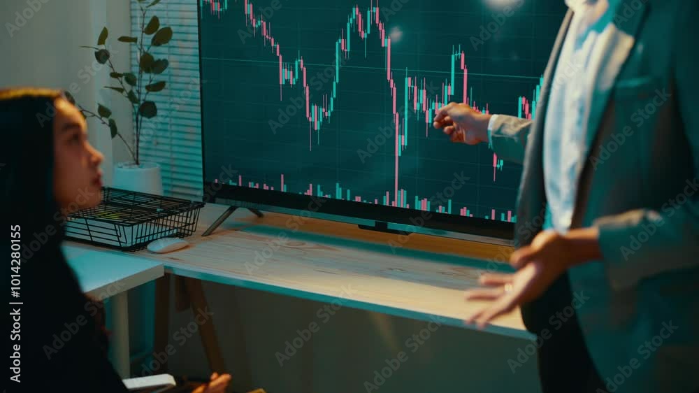 Poster Financial advisor points at a large screen displaying a stock market chart, explaining fluctuations and trends to a client during a detailed consultation in an office setting